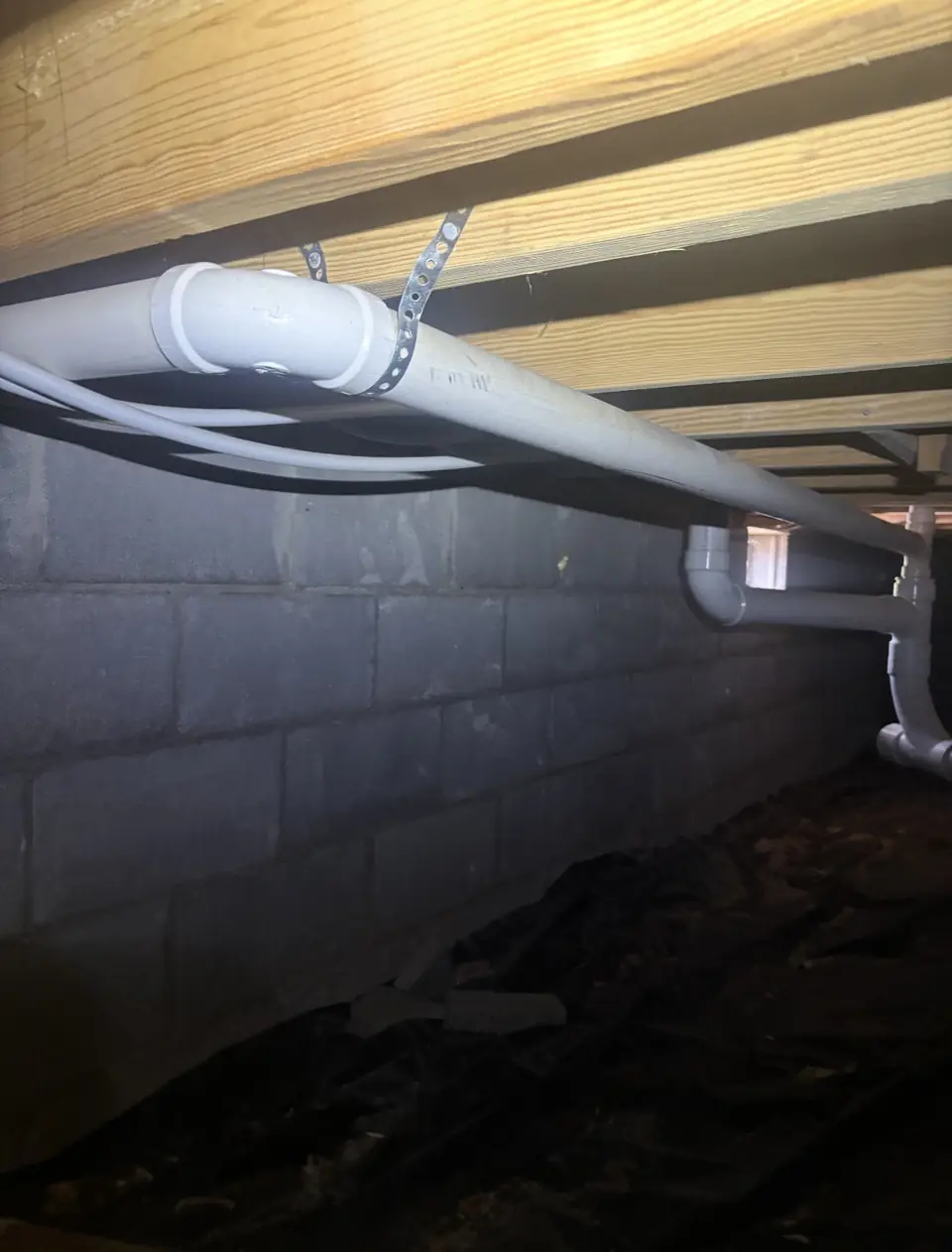 New PVC drain line run through a block crawlspace
