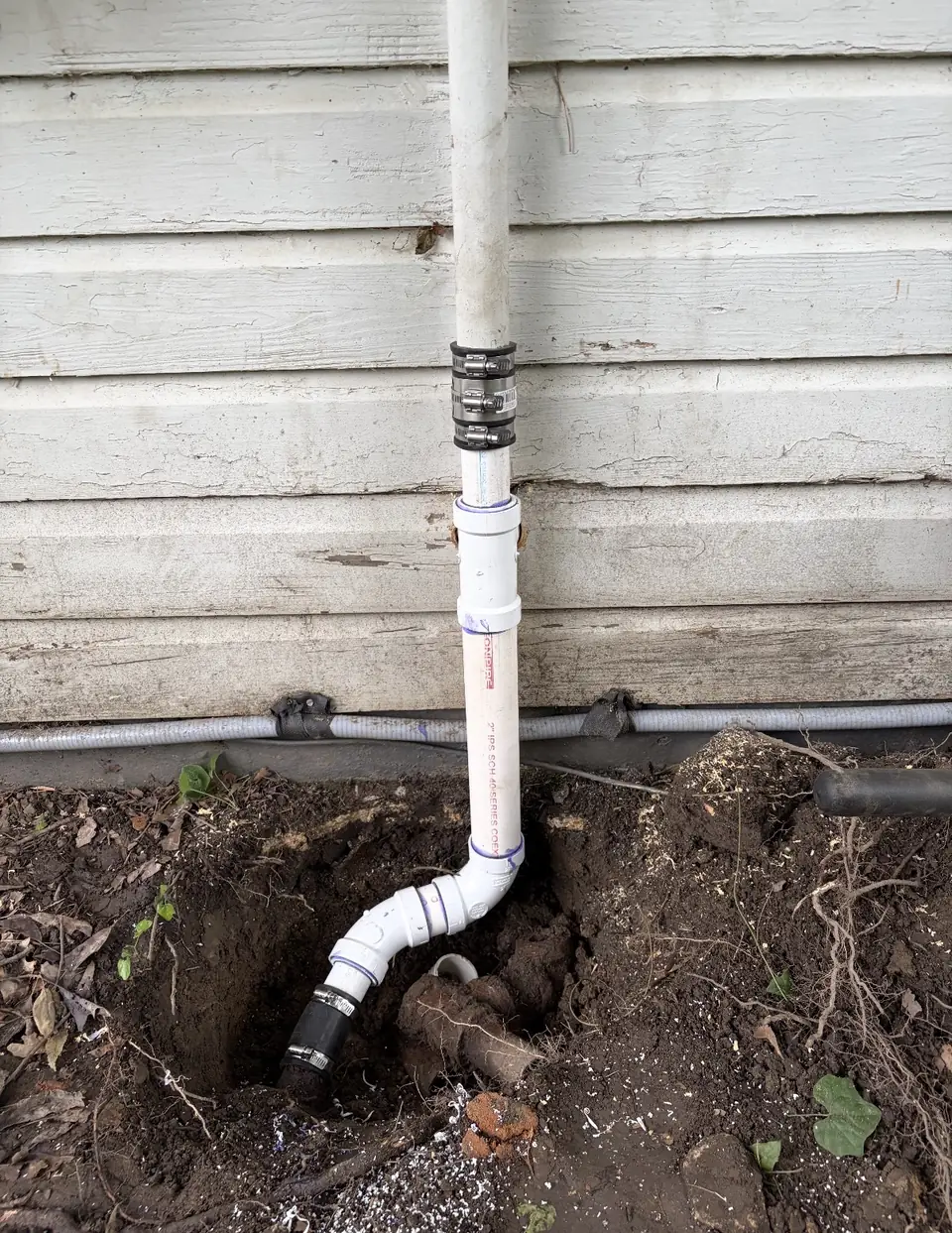 Sewer line repair in a dug trench beside a house
