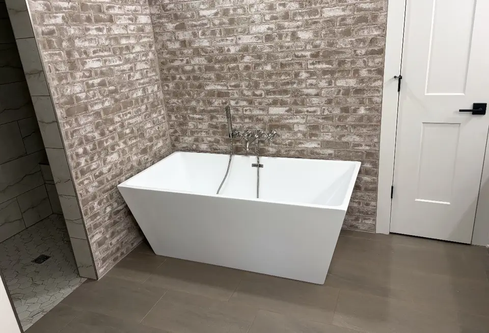 Freestanding tub installed against a stone accent wall